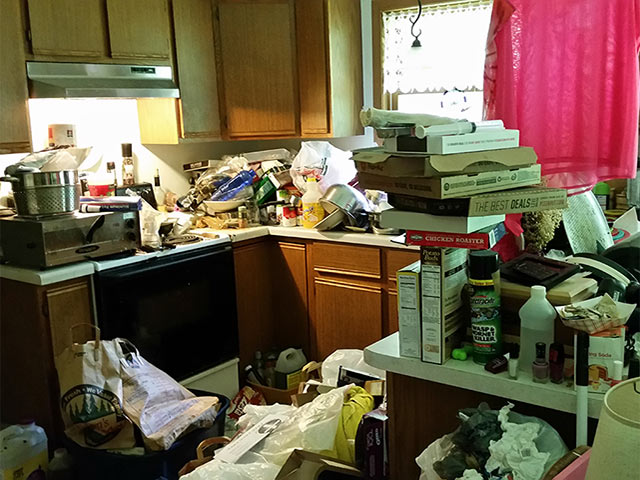 Hoarded kitchen packed with clutter before cleanup