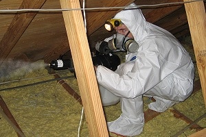 Technician in protective suit and respirator cleaning animal filth